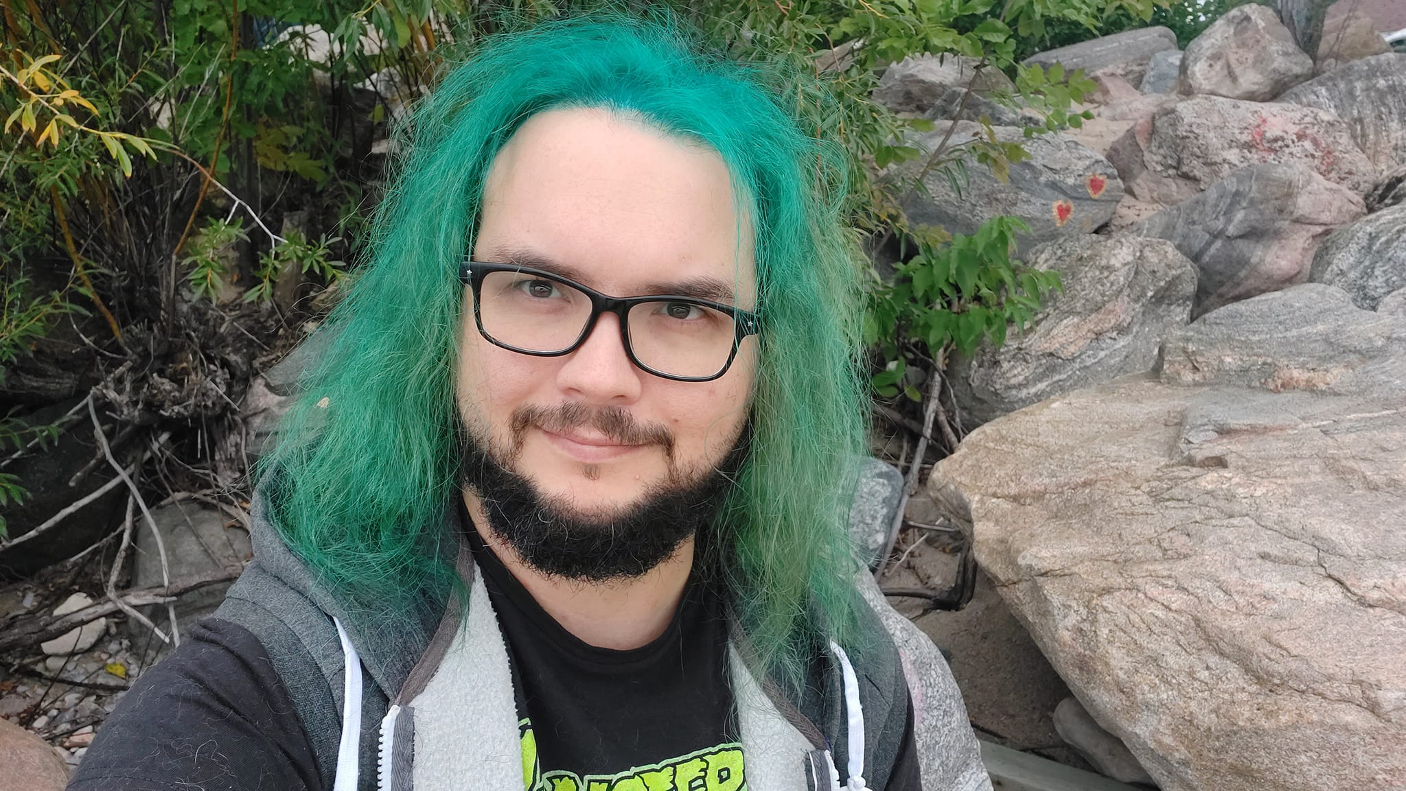 A man with green hair stands outside at a boulder breakwater, photo 10